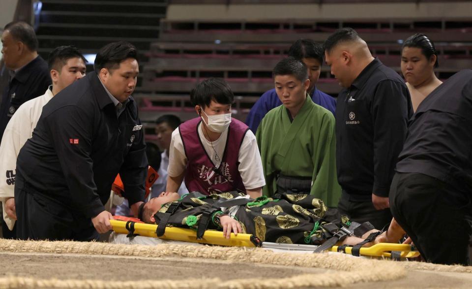 　担架で運ばれる行司の式守友三郎＝２３日