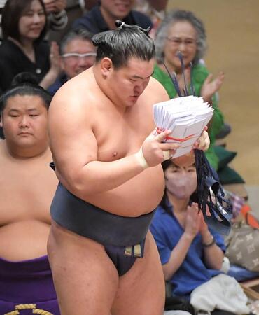 　分厚い懸賞の束を手にお辞儀する豊昇龍（撮影・佐藤厚）