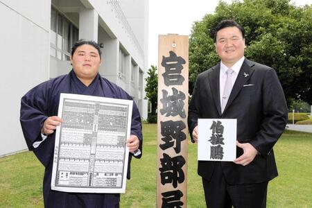　新入幕を果たし、番付を持つ伯桜鵬（左）としこ名を書いた色紙を持つ宮城野親方＝２３年６月