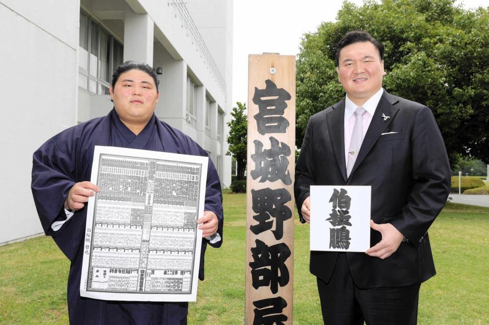 　新入幕を果たし、番付を持つ伯桜鵬（左）としこ名を書いた色紙を持つ宮城野親方＝２３年６月