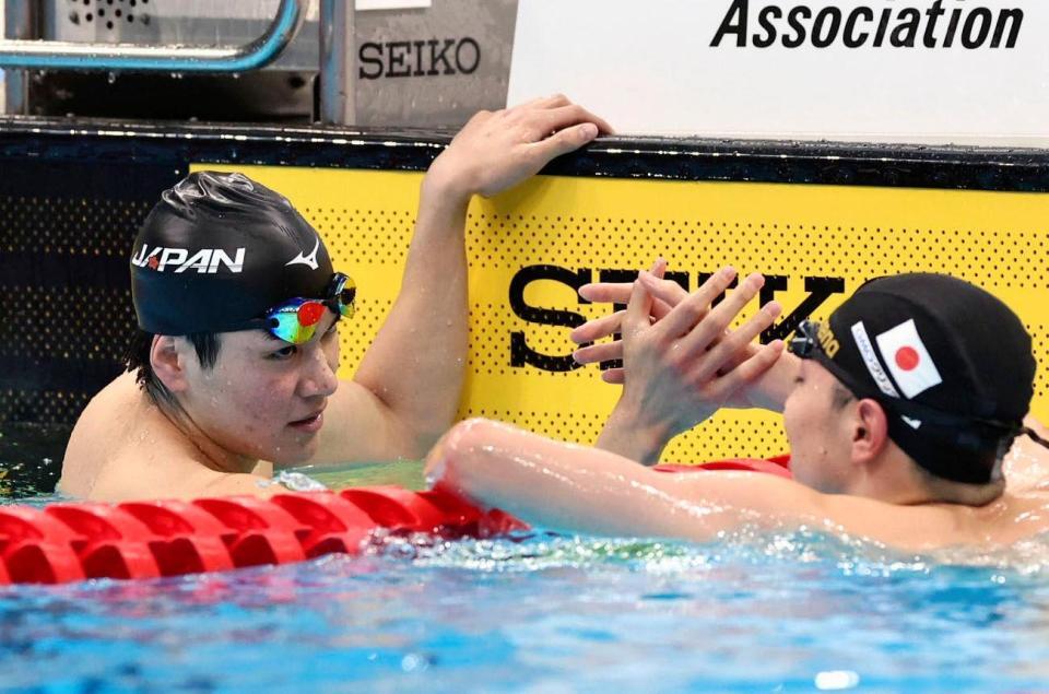 　男子４００メートル個人メドレーで優勝しタッチを交わす松下知之。右は２位の西川我咲