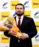 　花束を手に笑顔を見せるウルフ・アロン（撮影・佐藤厚）