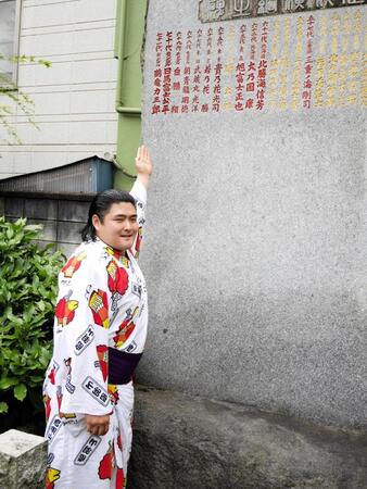 　横綱石碑に刻まれた師匠の音羽山親方のしこ名鶴竜に手を向ける今田