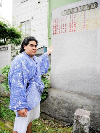 　叔父で師匠の武蔵川親方のしこ名・武蔵丸が刻まれた石碑に手を向ける光武蔵