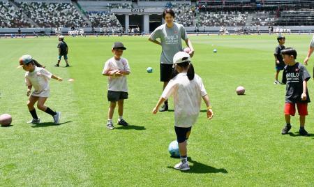 　マルチスポーツのイベントでサッカー体験する子どもたちを見守る、元男子日本代表の内田篤人さん（奥）＝２１日、東京・国立競技場