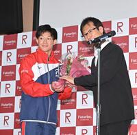 　壇上で花束を受け取る玉井陸斗（左）＝撮影・西田忠信