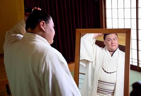 　記者会見でまげ姿を初披露し、鏡を見る新入幕の草野