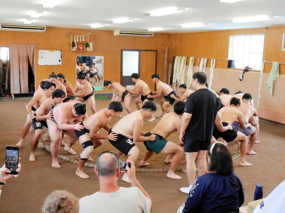 　安治川部屋力士と学生が土俵周りをすり足で歩く