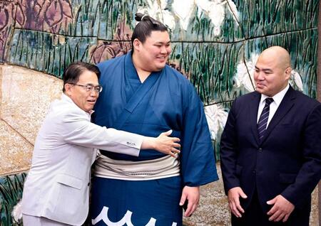 　表敬訪問した愛知県の大村秀章知事（左）に抱きつかれる大の里