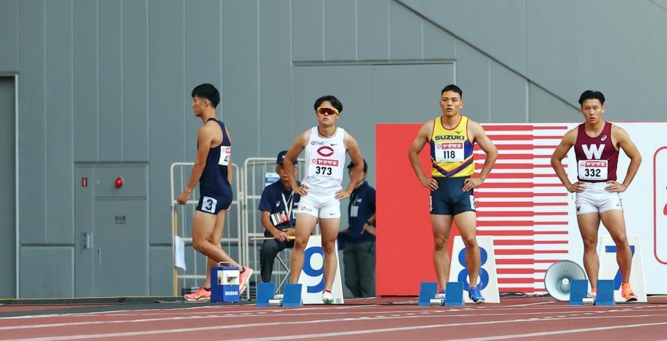 　男子１００メートル予選で失格になりコースを後にする柳田大輝（左）