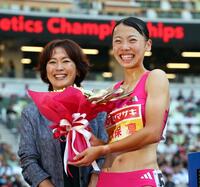 　女子８００メートルで優勝し花束を手に笑顔を見せる久保凛。左は日本陸連の有森裕子会長