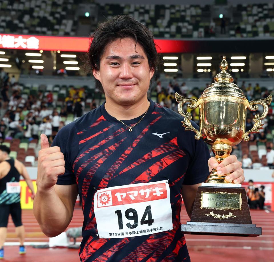 　男子やり投げで優勝し、トロフィーを手に笑顔を見せる崎山雄太