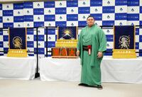 　贈呈された三つぞろいの化粧まわしを背に撮影に応じる大の里