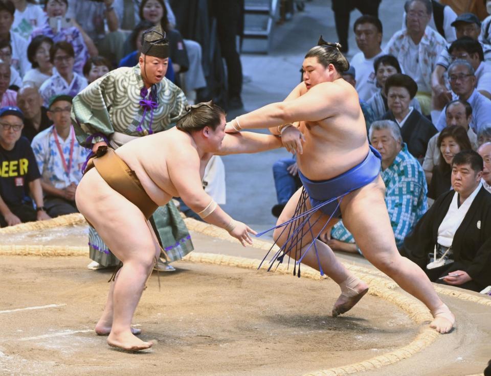 　王鵬（左）が押し出しで大の里を破る