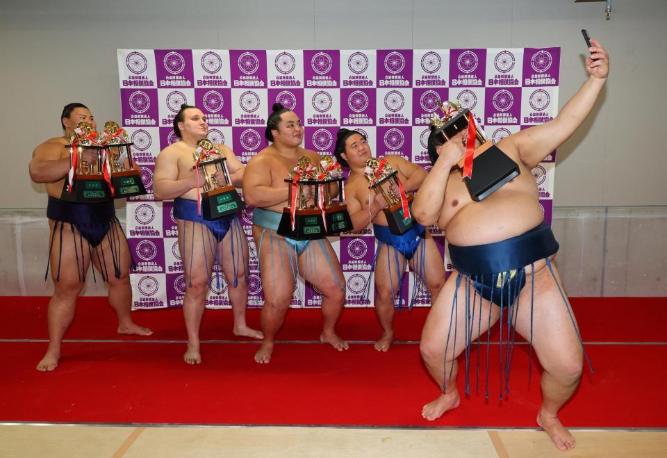 　玉鷲が手にするスマホで記念撮影する（左から）草野、安青錦、琴勝峰、藤ノ川（代表撮影）