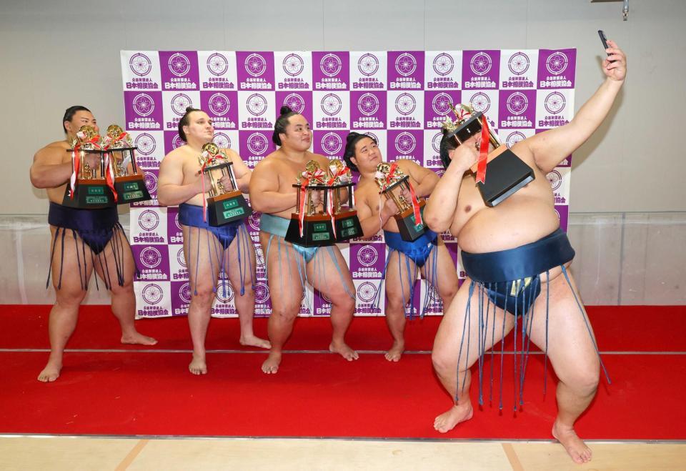 　玉鷲が手にするスマホで記念撮影する（左から）草野、安青錦、琴勝峰、藤ノ川（代表撮影）