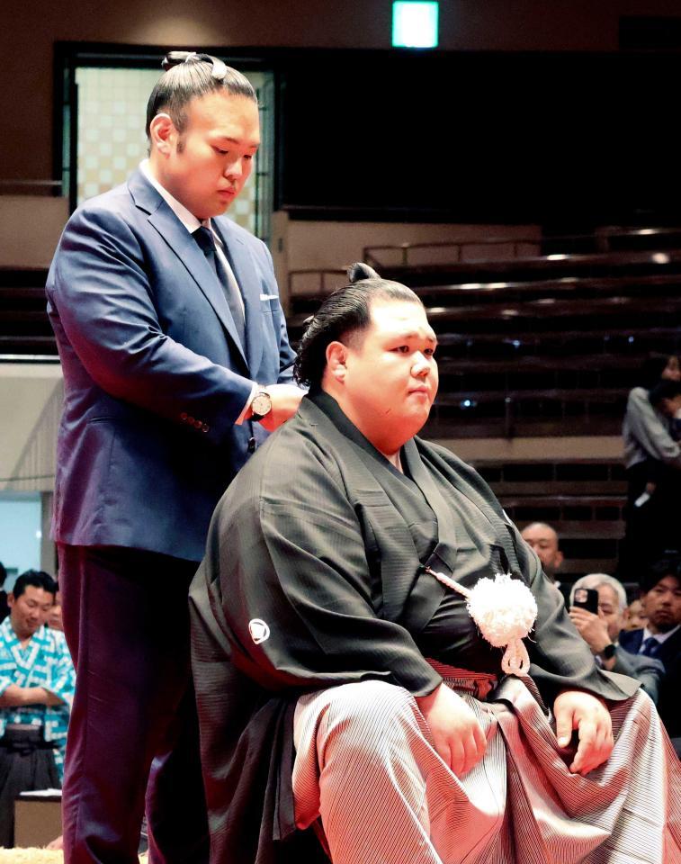 　断髪式で湊川親方（左）からはさみを入れられる元小結阿武咲＝６月