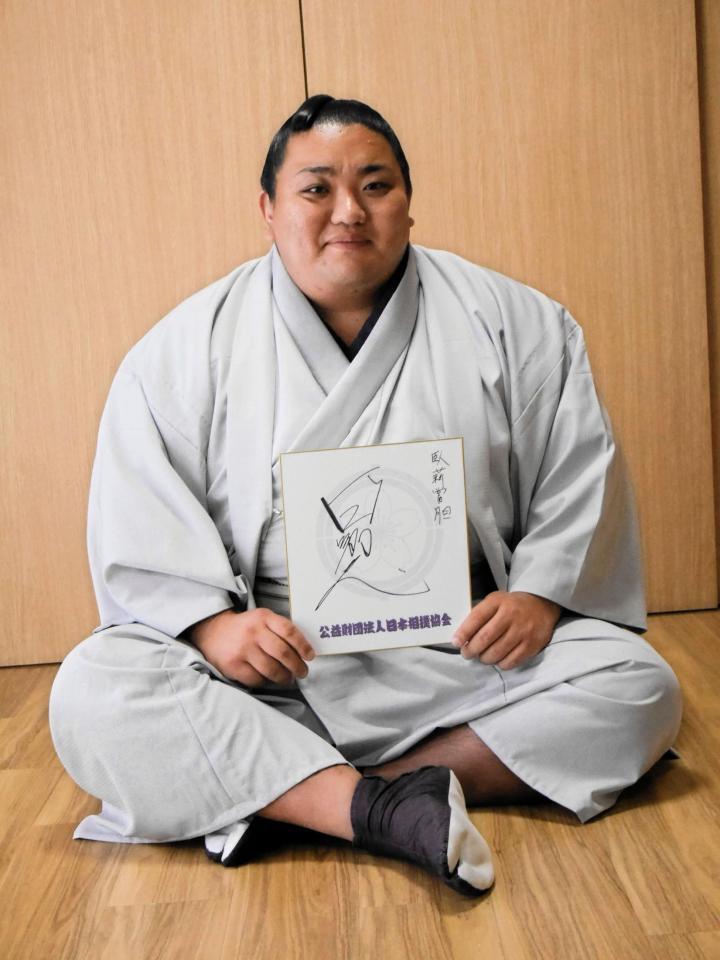 　「臥薪嘗胆」と記された色紙を手にする日翔志