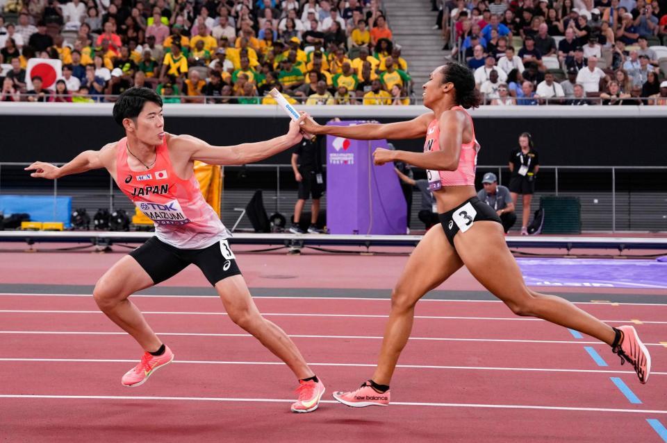 　混合１６００メートルリレー決勝で第２走者の井戸アビゲイル風果（右）からバトンを受け取る今泉堅貴