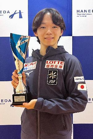 　トロフィーを手に撮影に応じるフィギュアスケート男子の鍵山優真＝１６日、羽田空港
