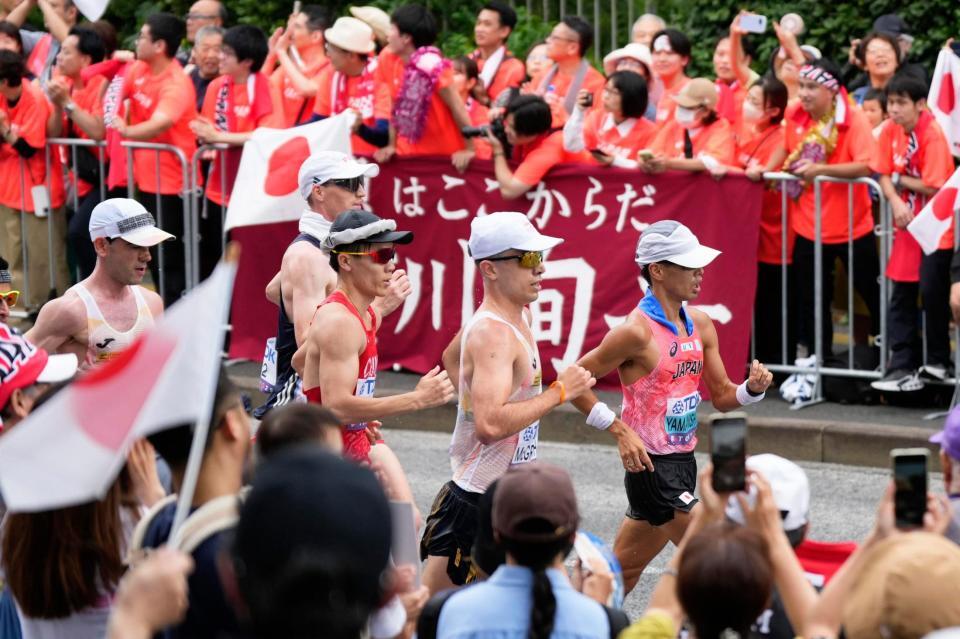 　沿道の声援を受け、懸命に歩く山西利和（右端）
