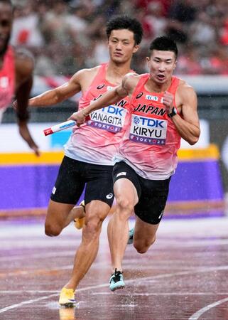 　２走の柳田大輝（左）からバトンを受け、力走する３走の桐生祥秀