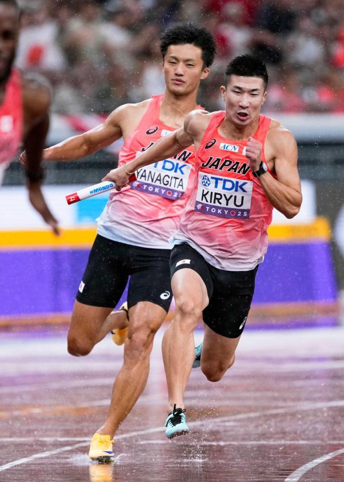 　２走の柳田大輝（左）からバトンを受け、力走する３走の桐生祥秀