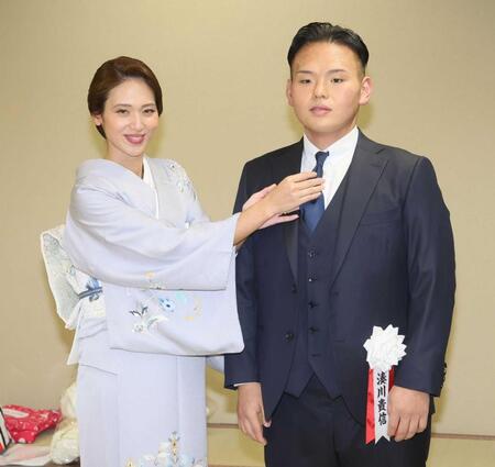 　有希奈夫人（左）にネクタイを直してもらう湊川親方（撮影・石井剣太郎）　