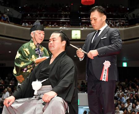 　はさみを入れる湊川親方（右）＝撮影・佐藤厚