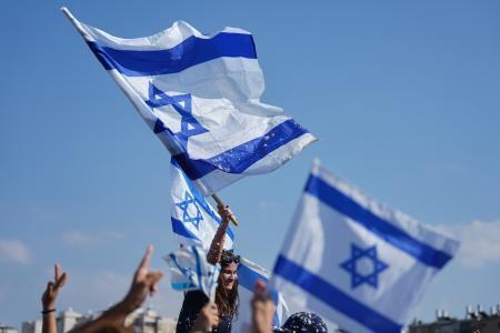 　イスラエルの国旗を持つ人たち＝１３日、イスラエル・テルアビブ近郊（ＡＰ＝共同）