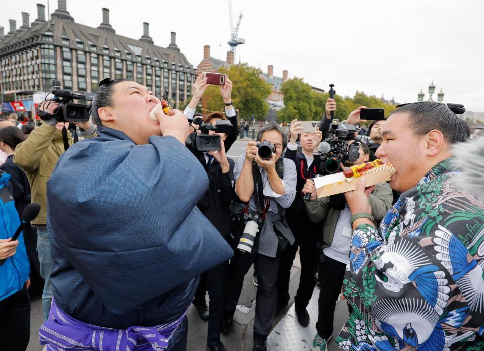 ロンドン市内でホットドッグを頰張る大の里（左）と豊昇龍の両横綱（共同）