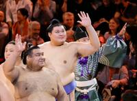 　閉会式を終えて手を振り引き揚げる横綱大の里（中央）ら（共同）
