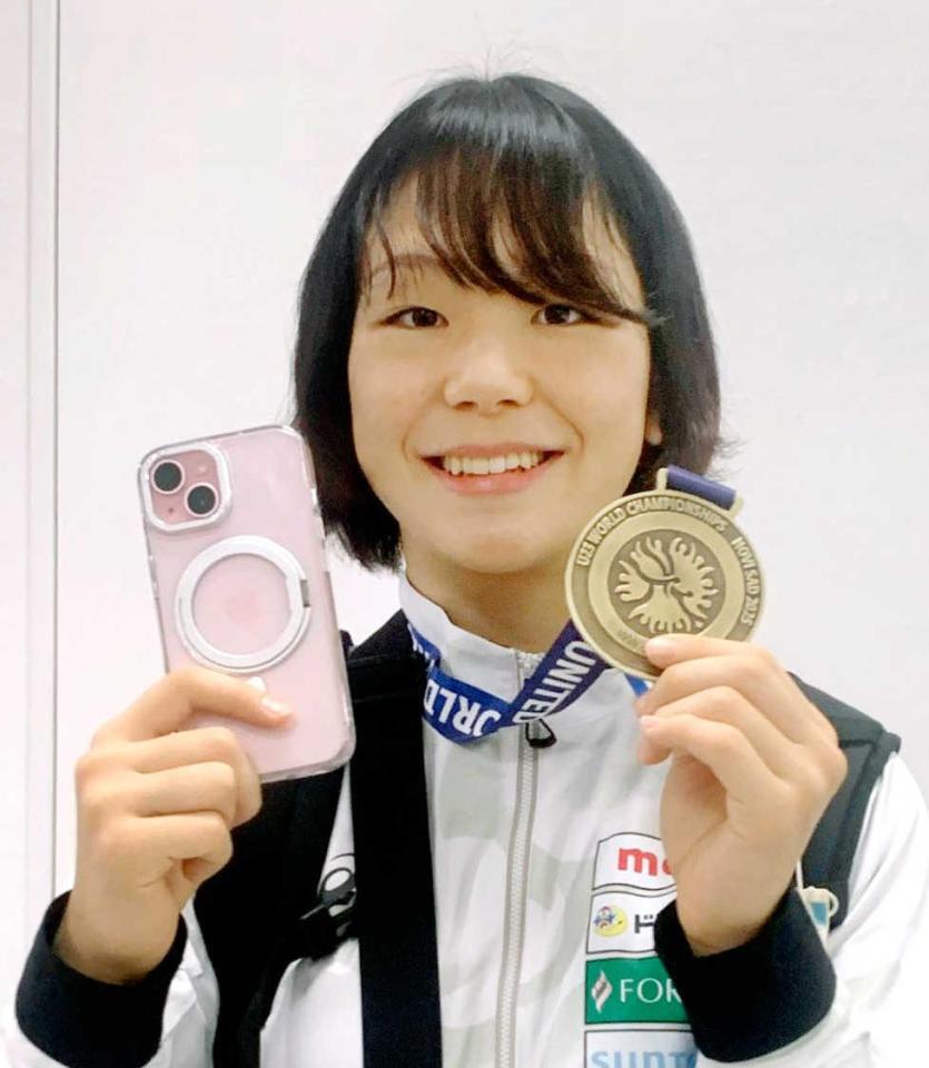 　金メダルと手元に戻ったスマートフォンを手に笑顔を見せる藤波朱理