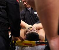 　取り組み中に足を負傷し、ストレッチャー上で顔を覆いながら運ばれる三田（撮影・坂部計介）