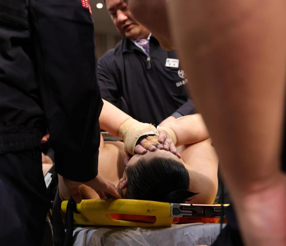 　取り組み中に足を負傷し、ストレッチャー上で顔を覆いながら運ばれる三田（撮影・坂部計介）