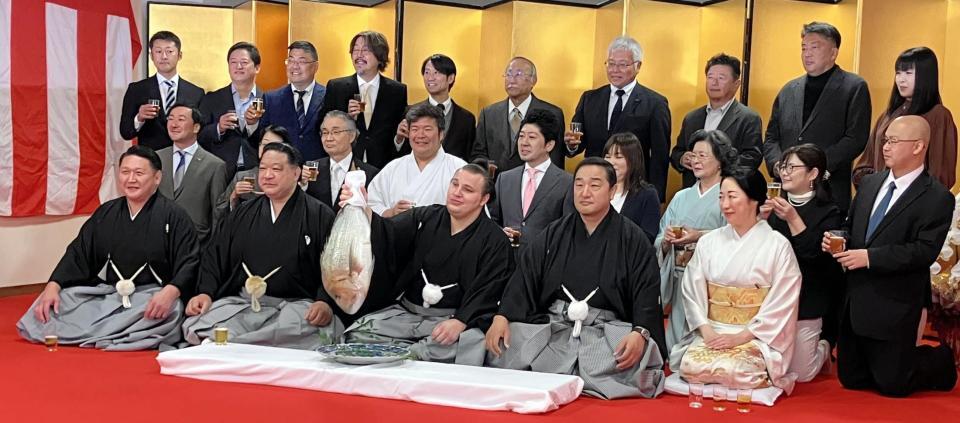 　鯛を手に笑顔の安青錦（中央）