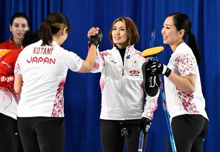 　トルコ戦の第６エンドで２点を挙げ、小谷（左）とタッチを交わす吉村。右は近江谷（共同）