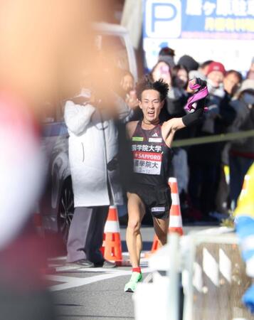 　平塚中継所で待つ飯国新太に向かってたすきを掲げ、ラストスパートする国学院大・高山豪起（撮影・吉澤敬太）