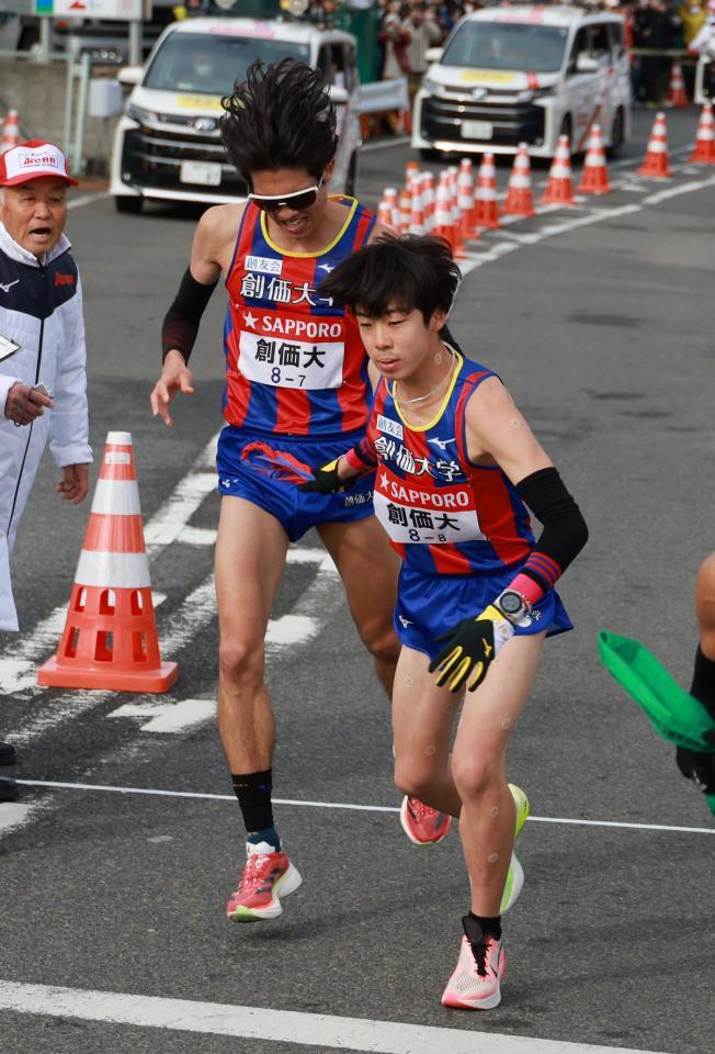 　平塚中継所でたすきをつなぐ創価大７区・石丸惇那（左）と８区・小池莉希＝代表撮影（２４年１月）