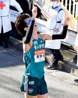 　タスキをつなぎ、天を指さす青学大・佐藤有（撮影・開出牧）