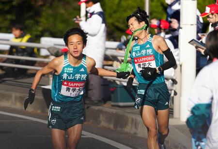 　８区、佐藤愛（右）からチームメートの名前がびっしりと書かれたたすきを受け取り、走り出す青学大・塩出＝３日