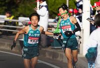 　８区、佐藤愛（右）からチームメートの名前がびっしりと書かれたたすきを受け取り、走り出す青学大・塩出＝３日