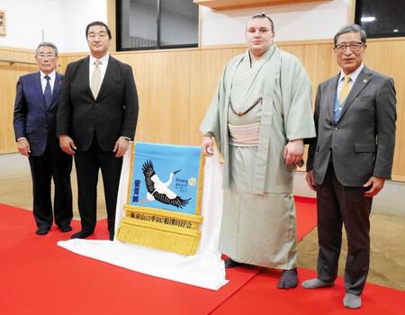 　新しい化粧まわしを挟む（左から）東京山の手ロータリークラブ相撲同好会の江中武久会長、安治川親方、安青錦、吉岡桂輔会長