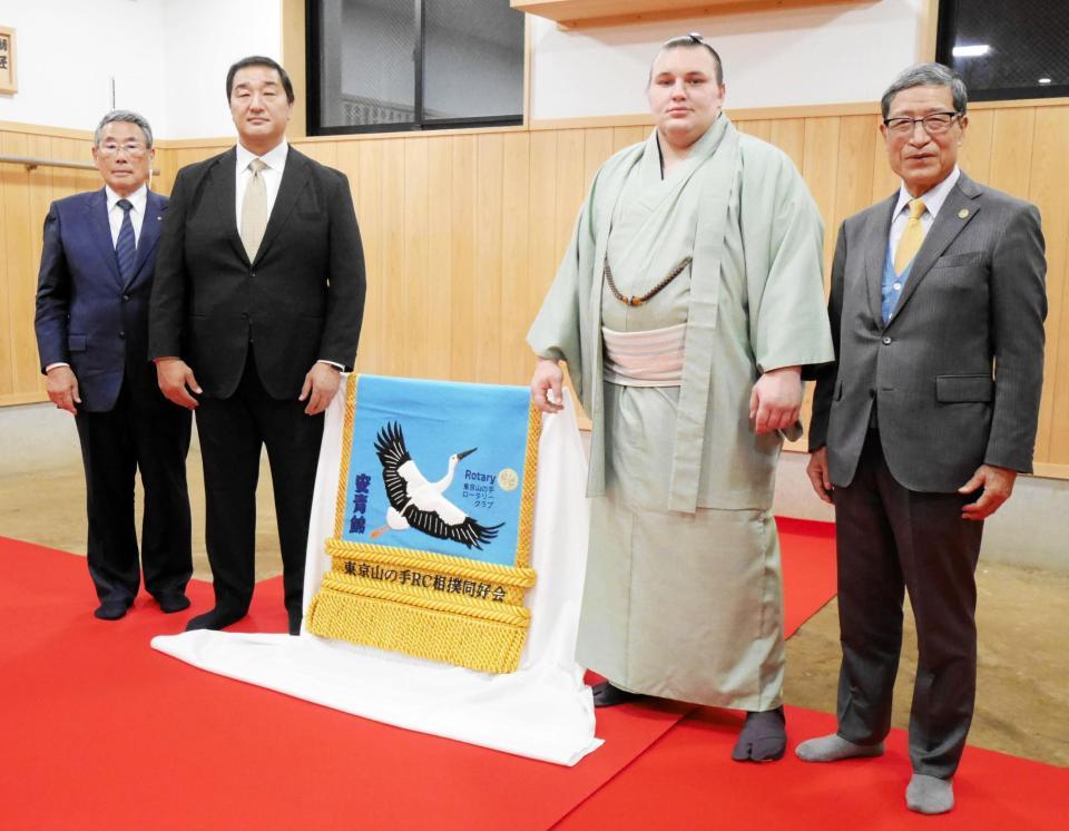 　新しい化粧まわしを挟む（左から）東京山の手ロータリークラブ相撲同好会の江中武久会長、安治川親方、安青錦、吉岡桂輔会長
