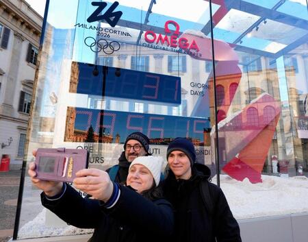 　ミラノ・コルティナ冬季五輪開幕までの日数を表示するカウントダウン時計前で、記念写真に納まる人たち＝６日、ミラノ（共同）