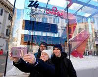 　ミラノ・コルティナ冬季五輪開幕までの日数を表示するカウントダウン時計前で、記念写真に納まる人たち＝６日、ミラノ（共同）