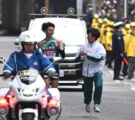 　９区、給水員から飲料を受け取る青学大・田中悠登（左）＝２０２５年１月３日