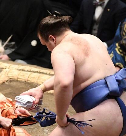 分厚い懸賞の束をわしづかみする安青錦（撮影・佐藤厚）