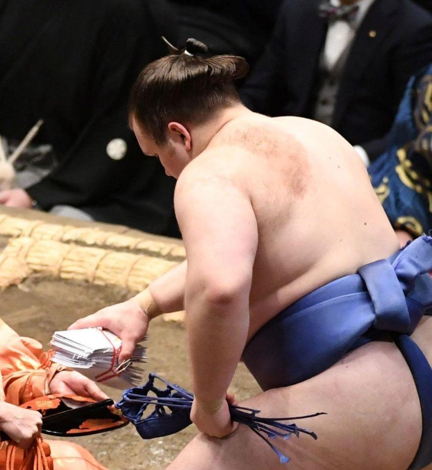 分厚い懸賞の束をわしづかみする安青錦（撮影・佐藤厚）