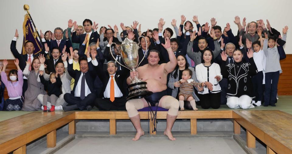 大相撲初場所で優勝し、賜杯を手に笑顔を見せる照ノ富士（中央）。その右は愛息の照務甚（てむじん）君と妻のドルジハンドさん＝２０２４年１月